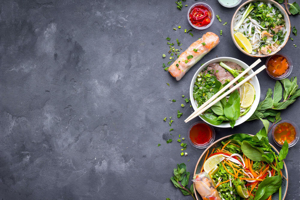 Assorted asian dinner, vietnamese food. Vietnamese noodle soup pho bo, pho ga, spring rolls, vegetable salad. Asian/vietnamese food background. Copy space. Traditional vietnamese dishes set. Top view