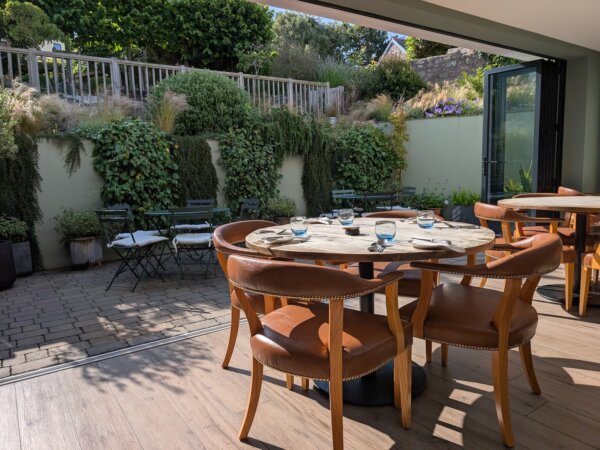 a table and chairs outside with a fence and plants