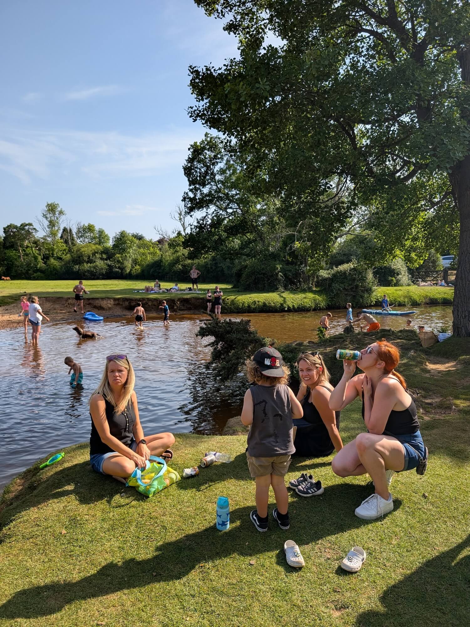 a group of people sitting on grass by a body of water